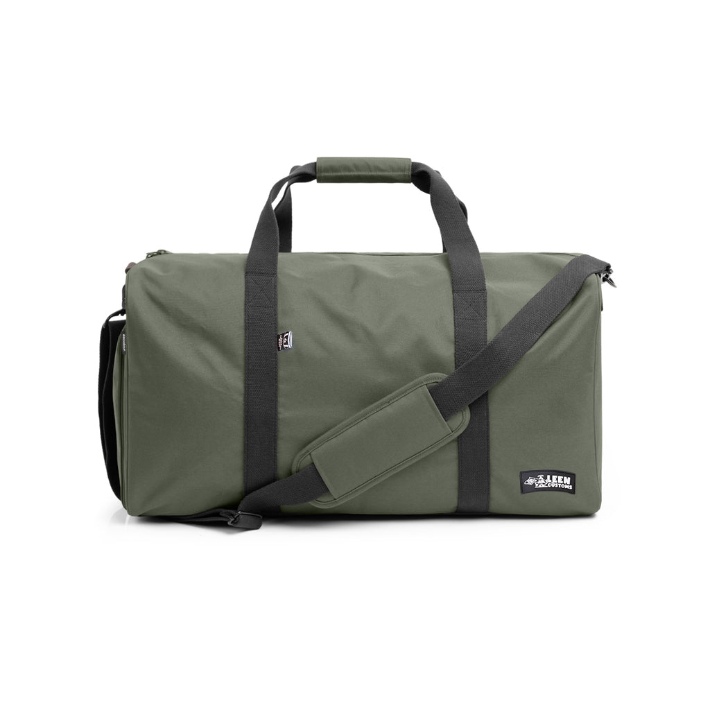 The Leen Customs Travel / Golf Bag in Cypress green! Custom made for your everyday essentials when you're on the road. Designed with simplicity in mind, a rectangular duffel with one large main compartment, one external shoe compartment and one small internal zipped pocket. Equipped with reinforced adjustable contrast shoulder strap and handles, size as follows 58cm X 28cm X 28cm  SPECS:  Crafted in Los Angeles CA Heavy weight, 10.3 oz 50L capacity 100% Recycled Polyester