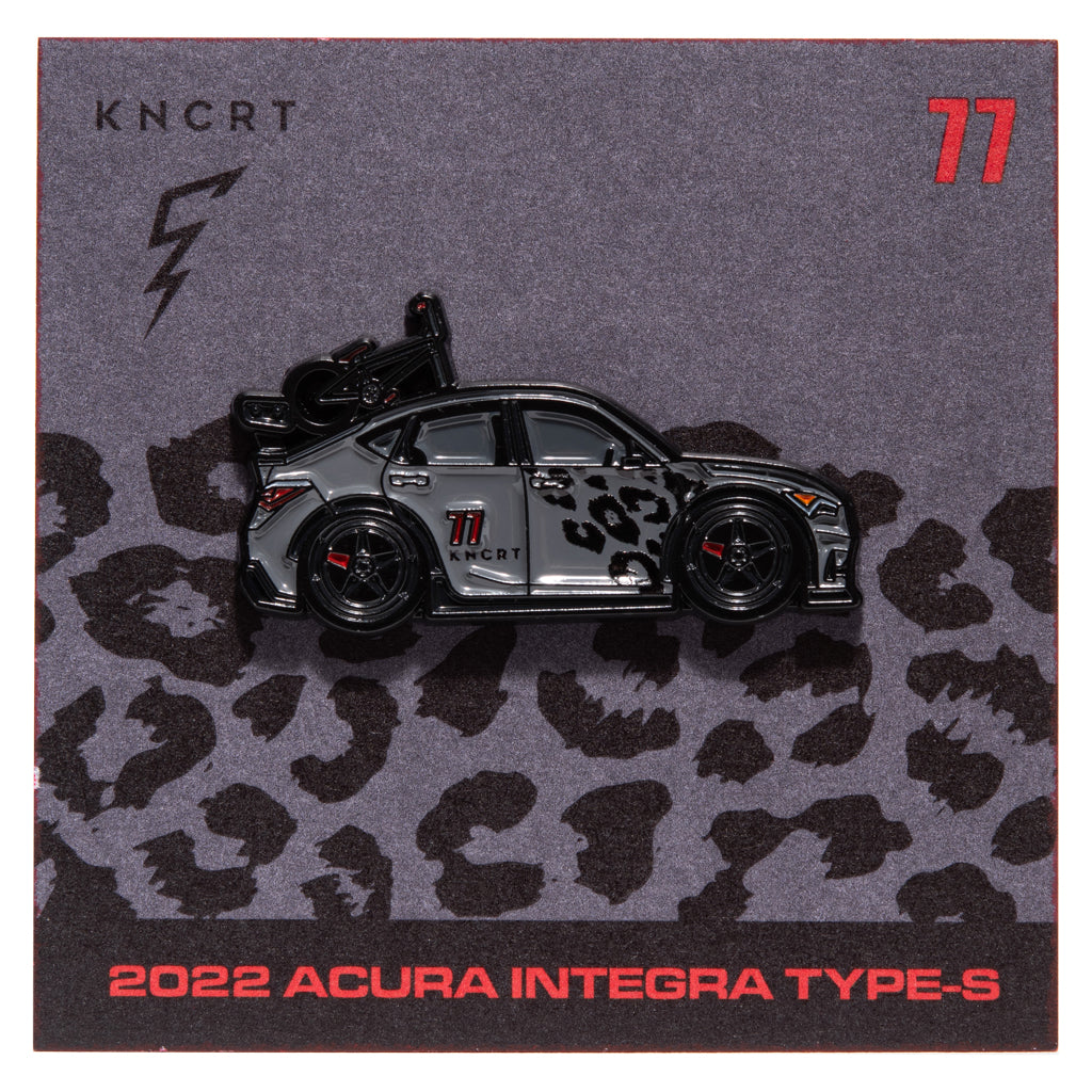 Metal enamel pin of a 2022 Acura Integra Type-S in dark grey with black leopard print across the front passenger door. With black 5 spoke wheels, one spoke being red. Equipped with black fender flares and bmx bike mounted the the rear. With wing. On backing card with similar design as the car and KNCT logo.