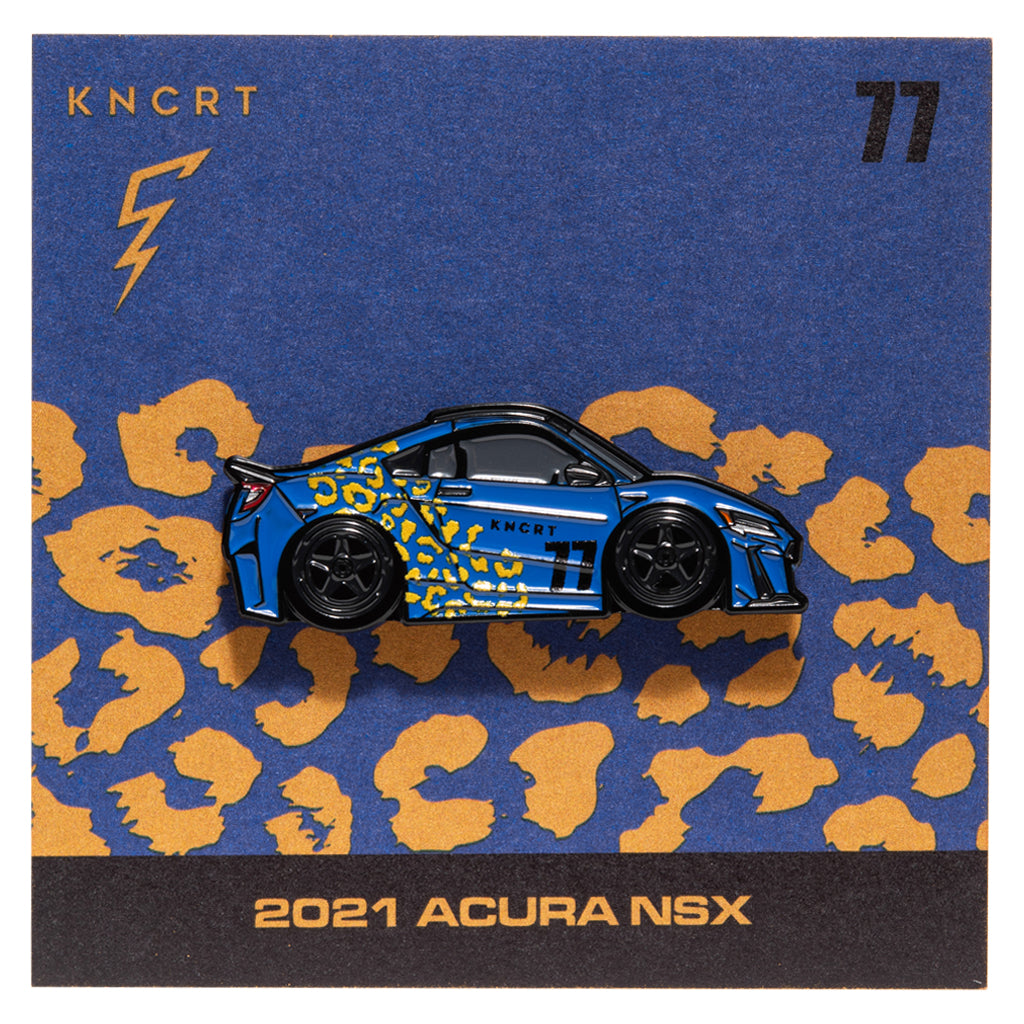 Metal enamel pin of a 2021 Acura NSX in blue with yellow leopard print and black wheels. On backing card resembling the car's design with KNCRT logo.