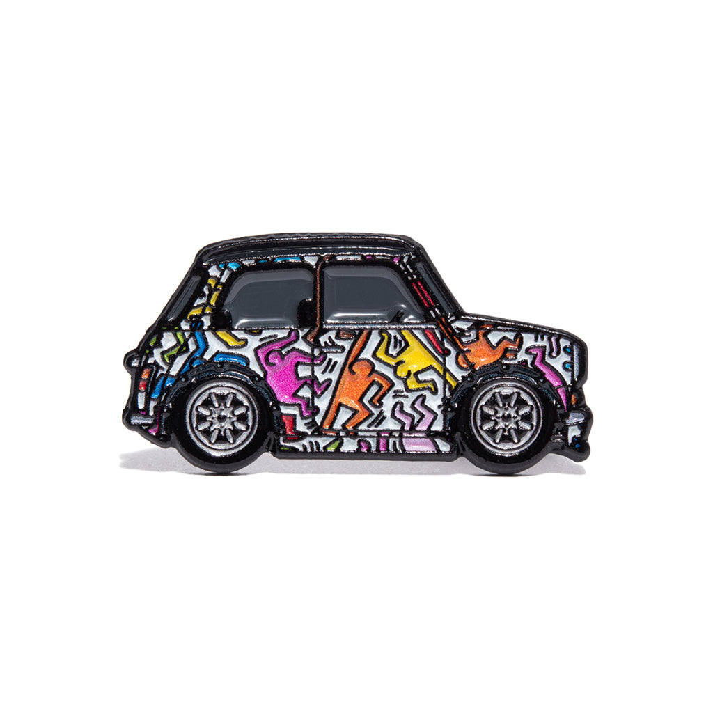 Metal enamel pin of a classic Mini with human figures dancing in Keith Haring style. Colors: white, orange, pink, blue, yellow. Equipped with silver Minilite wheels.