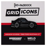 Metal enamel pin of a 1986 Ford Mustang GT in black with black wheels. On black, white, and red backing card with Pit+Paddock logo. In collaboration with Vibrant Performance and Weld Racing.