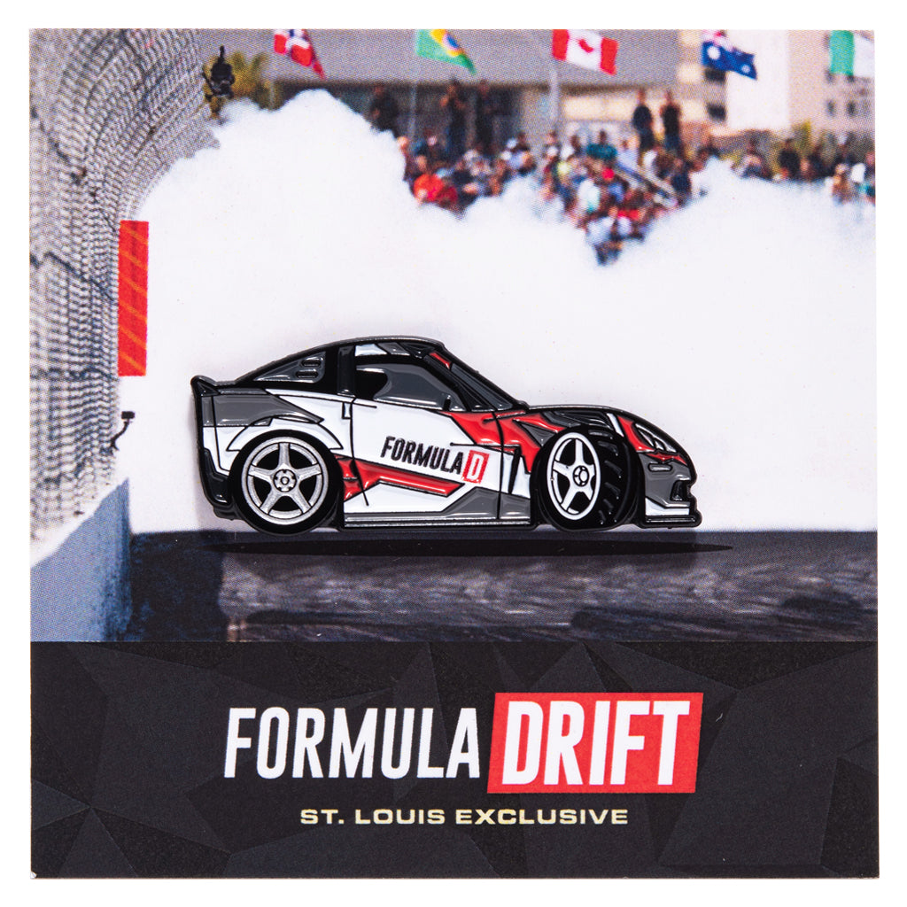 Metal enamel pin of a C6 Corvette with custom Formula D livery. Colors: white, red, grey with silver rear wheel and white front wheel. Front wheel is in full lock to simulate a drift in motion. On backing card resembling a fenced skid pad with smoke to emulate a drift in motion.