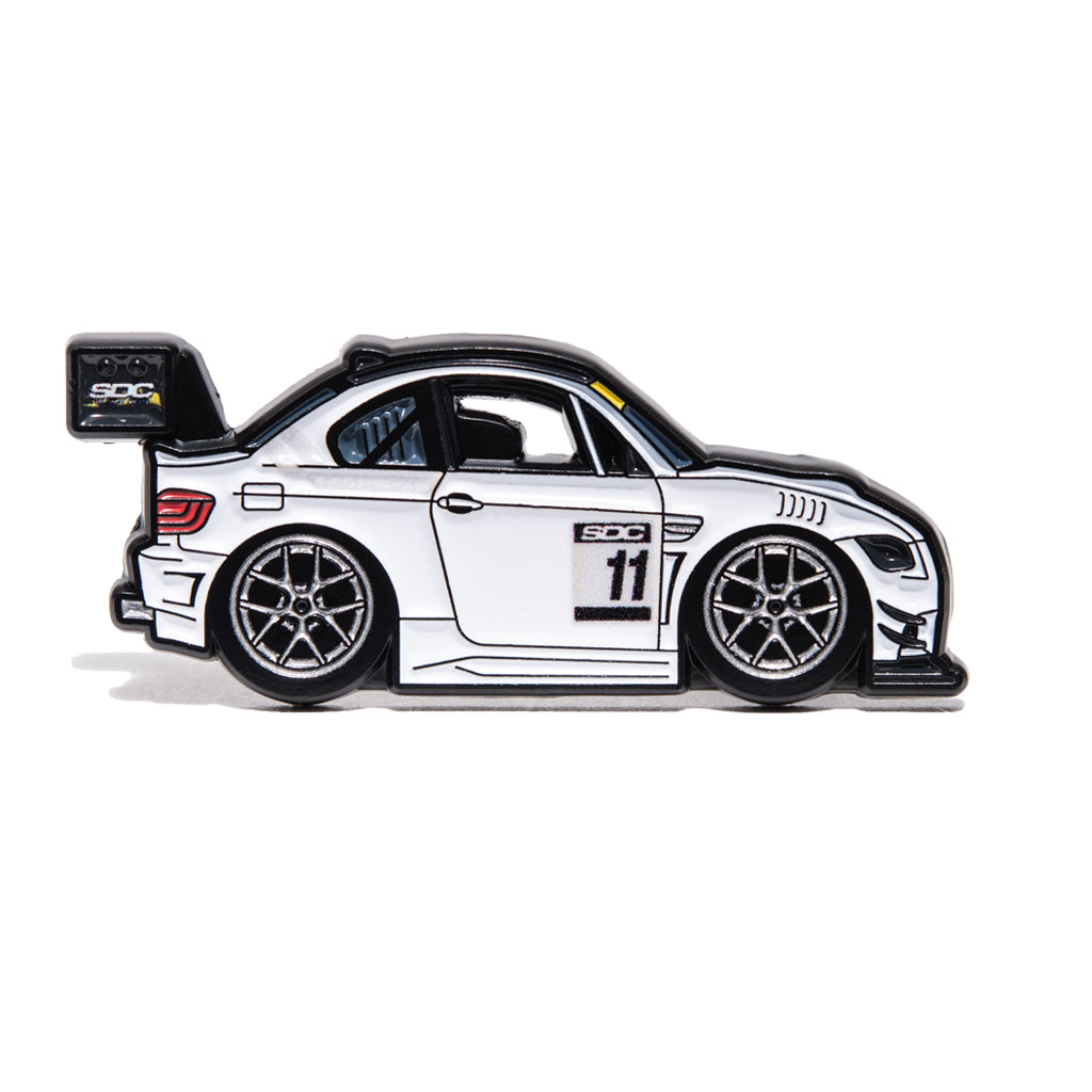 Enamel pin of a white BMW E92 with #11 on it. 