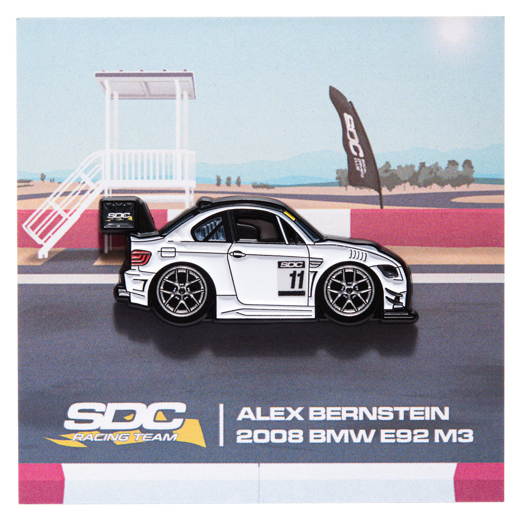 Enamel pin of a white BMW E92 with #11 on a racing track backing card for SDC Racing Team, Alex Bernstein