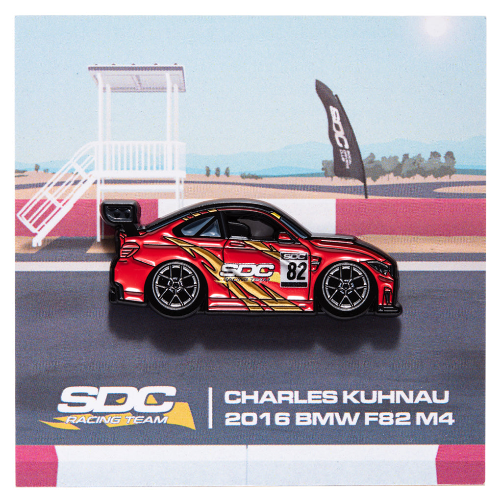Enamel pin of a red livery F82 M4 with a racing track backing card. 