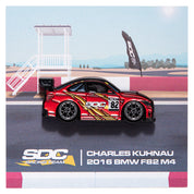 Enamel pin of a red livery F82 M4 with a racing track backing card. 