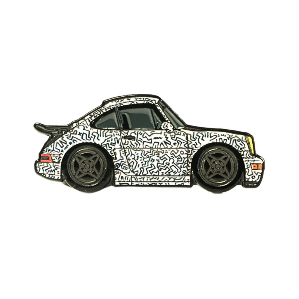 A soft enamel lapel pin depicting a Porsche 964 with a Keith Haring inspired livery.