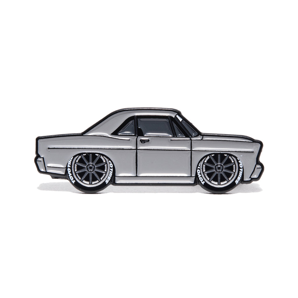 Metal enamel pin of 1967 Ford Galaxie Fastback built by Shaun Dickie at Americarna Workshop Services in grey with dark grey wheels.