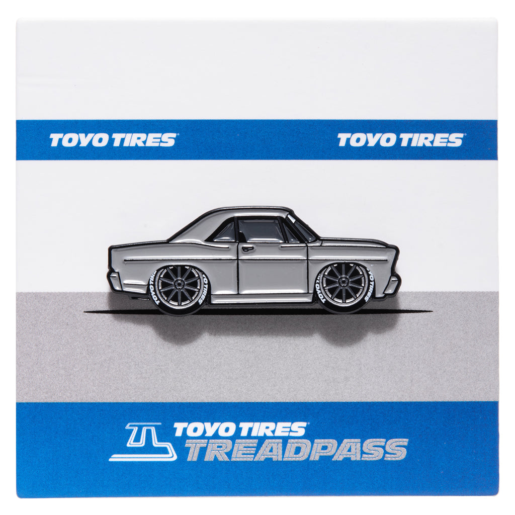 Metal enamel pin of 1967 Ford Galaxie Fastback built by Shaun Dickie at Americarna Workshop Services in grey with dark grey wheels. On grey and blue backing card with Toyo Tires Treadpass logo.