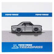 Metal enamel pin of 1967 Ford Galaxie Fastback built by Shaun Dickie at Americarna Workshop Services in grey with dark grey wheels. On grey and blue backing card with Toyo Tires Treadpass logo.